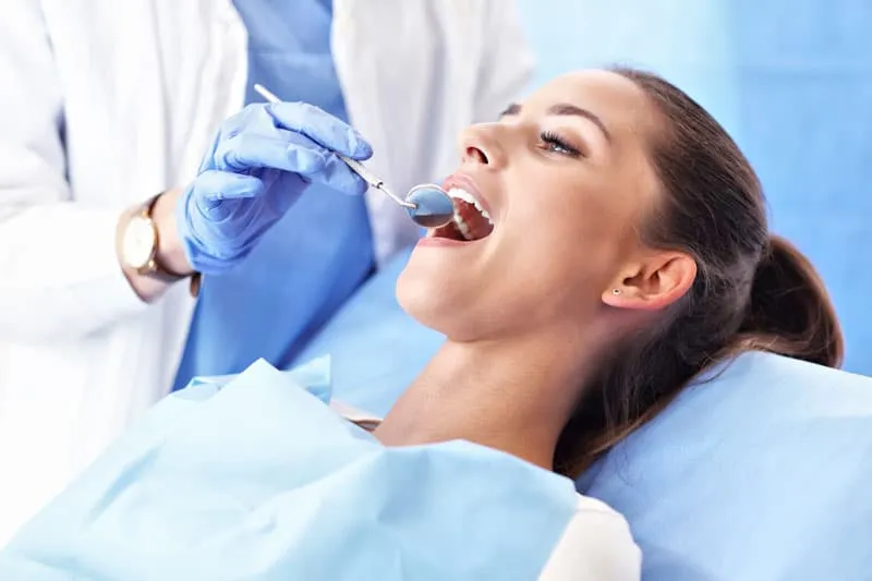 Odontóloga revisando la boca de una paciente en el sillón dental de la Clínica Dentalbeth